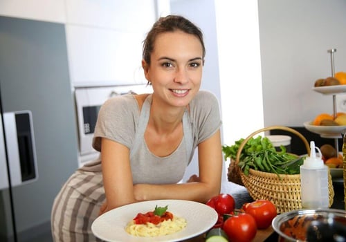 Woman in kitchen preparing pasta dish