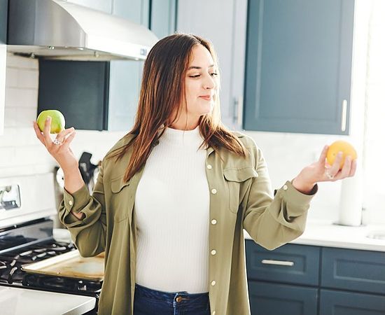 person holding an apple and an orange in each hand